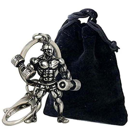 Een metallic stijlvolle bodybuilder sleutelhanger, waarbij de sleutelhanger vastzit aan een grote ring, naast een klein zwart tasje met trekkoord.