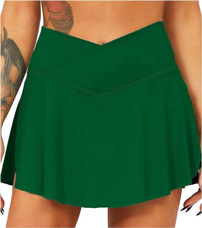 Load image into Gallery viewer, Close-up van een groene tennisrok met broek van een vrouw met een zichtbare tatoeage op haar bovenarm.
