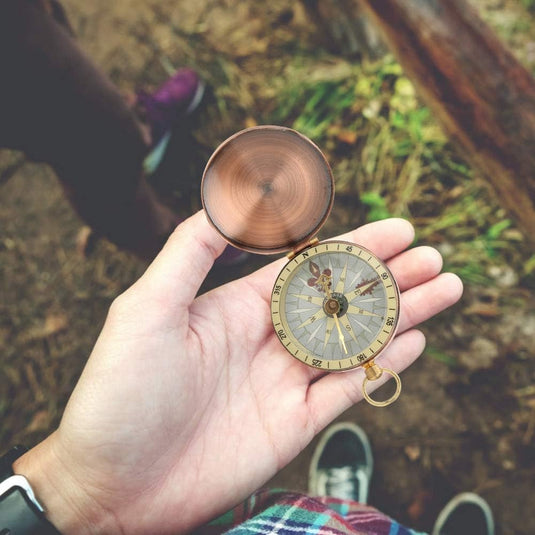 Een outdoorliefhebber met een vintage koperen kompas: een klassiek hulpmiddel voor outdoorliefhebbers in de hand.