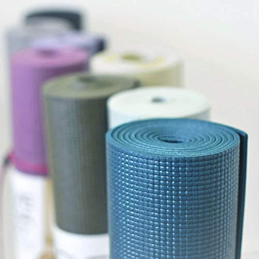 Stapel verschillend gekleurde yogamatten - Optimale grip en comfort voor elke yogavorm op een rij gerangschikt, met de nadruk op een blauwe mat op de voorgrond, voorbereid voor een yogasessie.
